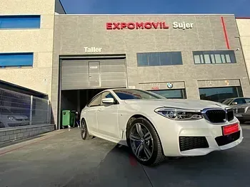 Un BMW blanco está estacionado frente a un edificio.