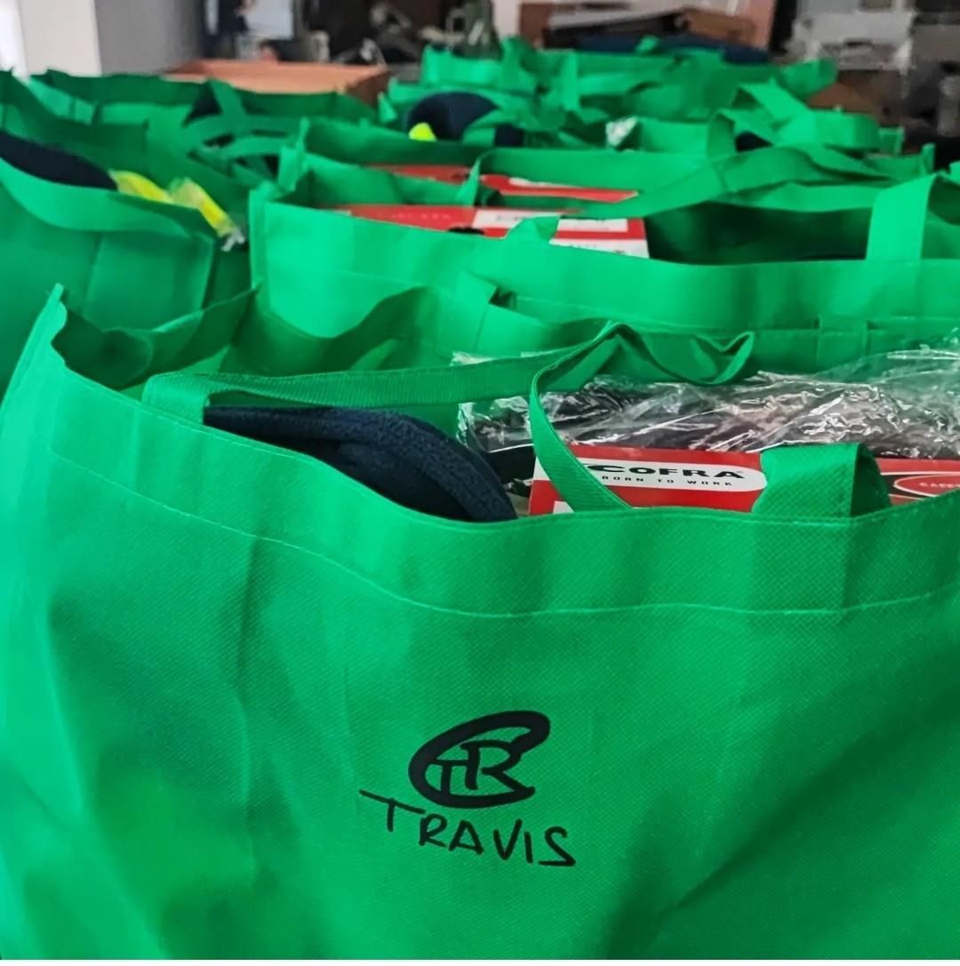 Una hilera de bolsas reutilizables de color verde brillante, cada una con un logotipo circular negro y el texto