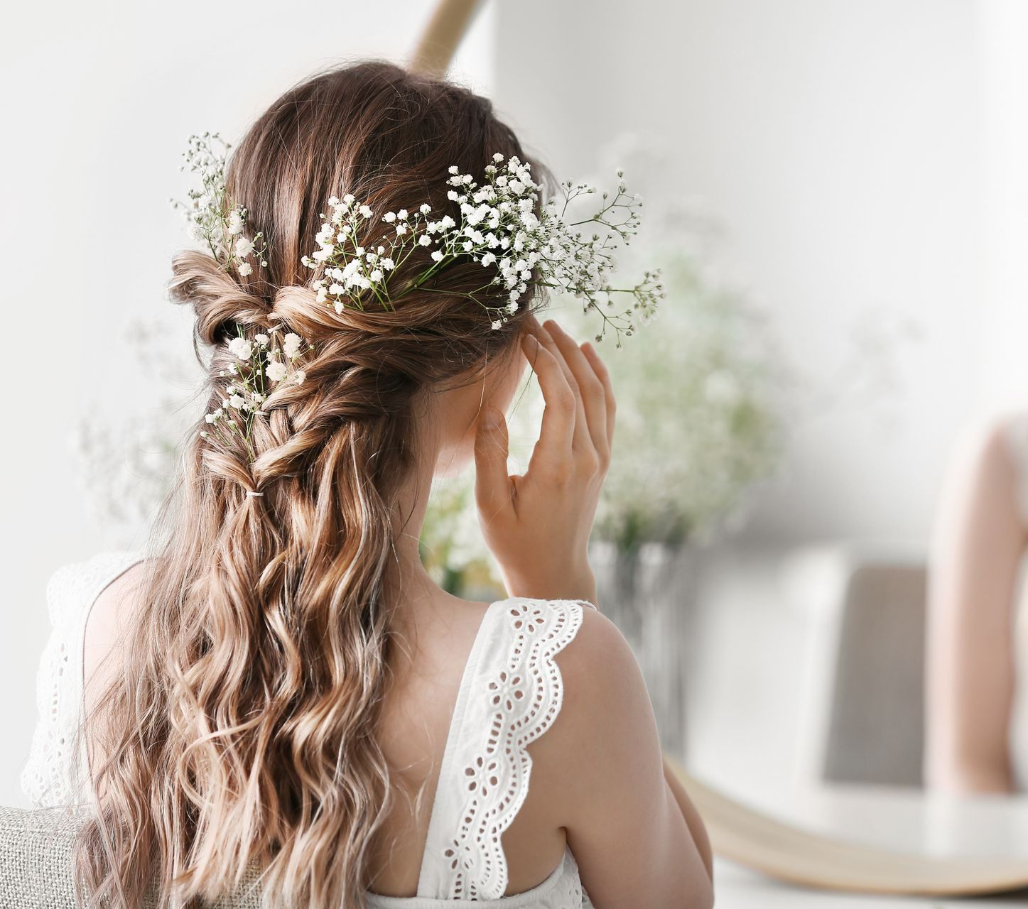 Une femme de dos avec des fleurs dans les cheveux.