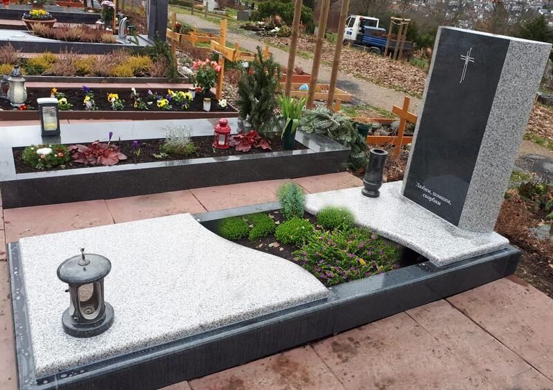 Granitgrabstein mit weißem Kies, Blumen und einer kleinen Laterne auf einem Friedhofsfriedhof