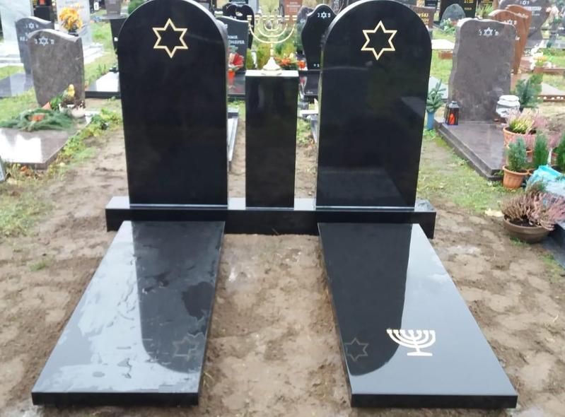 Schwarze Zwillingsgrabsteine ​​mit goldenen Sternen und Symbolen auf einem Friedhof