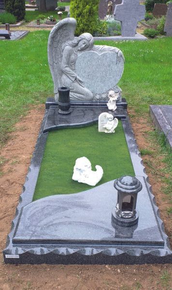 Grabstein mit Engelsstatue und herzförmigem Grabstein auf einem grünen Friedhofsplatz