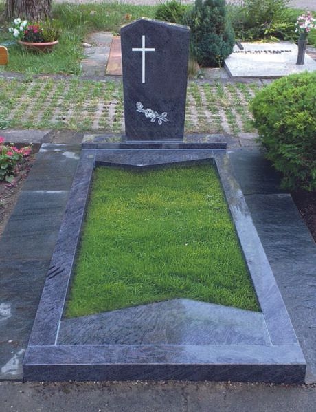 Schwarzes Granitgrab mit weißem Kreuz und grüner Rasenfläche auf einem Friedhof