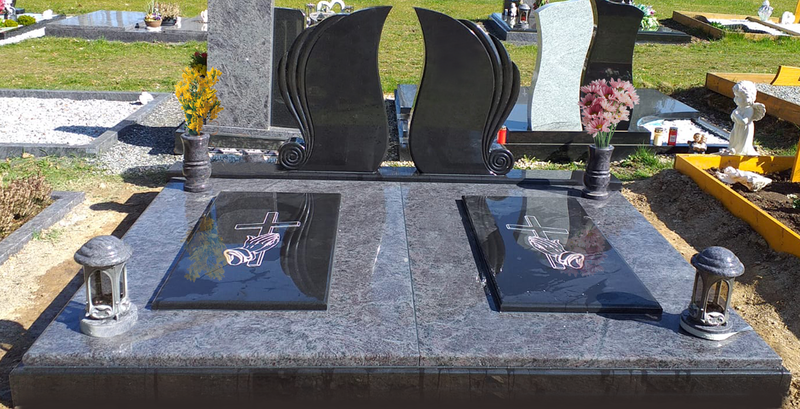 Schwarzer Granitgrabstein mit zwei eingelassenen Gedenktafeln und Blumenvasen auf einem Grab.