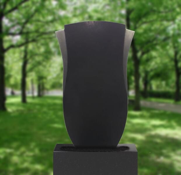 Dunkle, abstrakte Skulptur auf einem Sockel vor verschwommenem, grünem Parkhintergrund