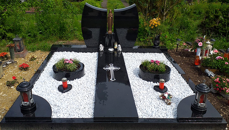 Schwarz-weißer Gedenkgarten mit Blumen, Kerzen und einem zentralen kreuzförmigen Steinweg