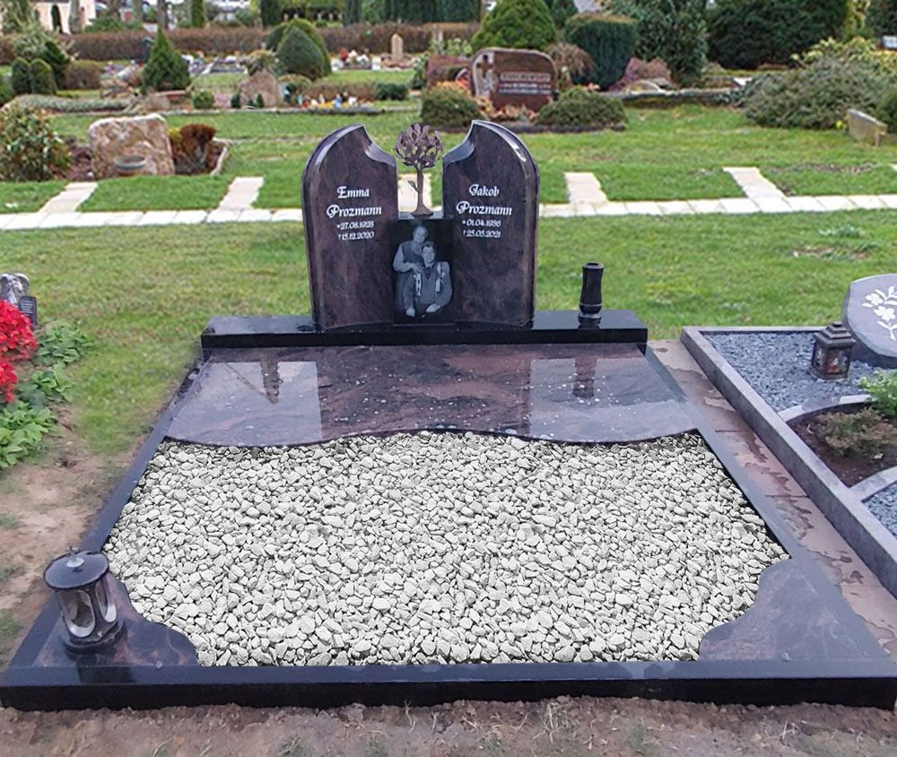 Doppelgrabstein aus schwarzem Granit mit weißem Kiesrand in einem Friedhofsgarten, dahinter gestutzte Sträucher.