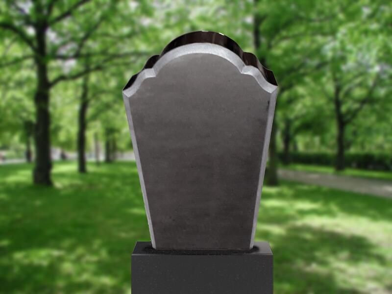 Grauer Grabstein in einem grünen Park, im Hintergrund verschwommene Bäume