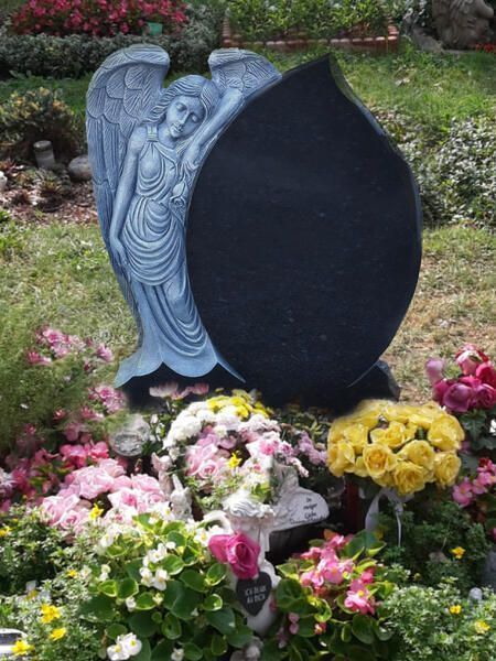 Grauer Engelsgrabstein mit dunkler ovaler Gedenktafel, umgeben von rosa und gelben Blumen in einem Garten