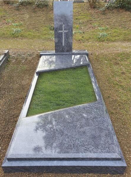 Moderner Grabstein mit schrägem grauen Stein und rechteckigem Rasenbereich auf einem Friedhof