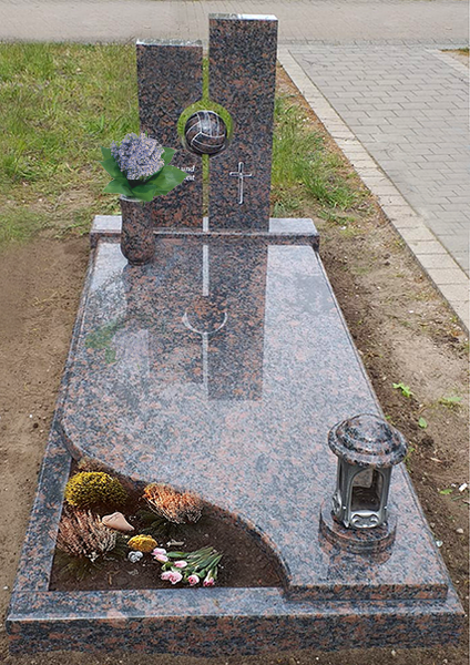 Gedenkgrab mit polierter Granitplatte, Blumen und einer kleinen Laterne an einem gepflasterten Weg