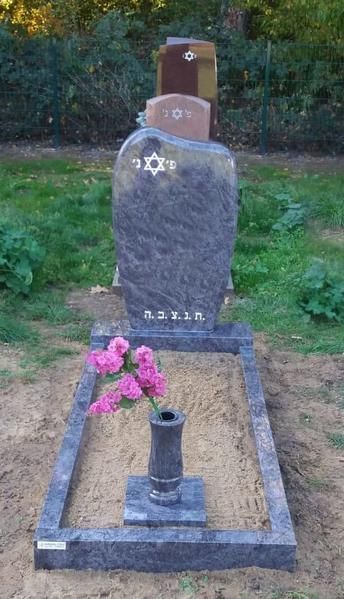 Grabstein mit einer kleinen Vase rosa Blumen auf einem grasbewachsenen Friedhofsgelände