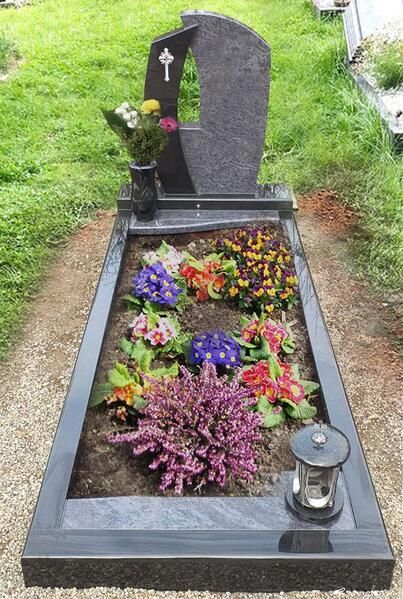 Grabstätte mit schwarzem Granitgrabstein, bunten Blumen und einer Laterne auf einer grasbewachsenen Friedhofswiese