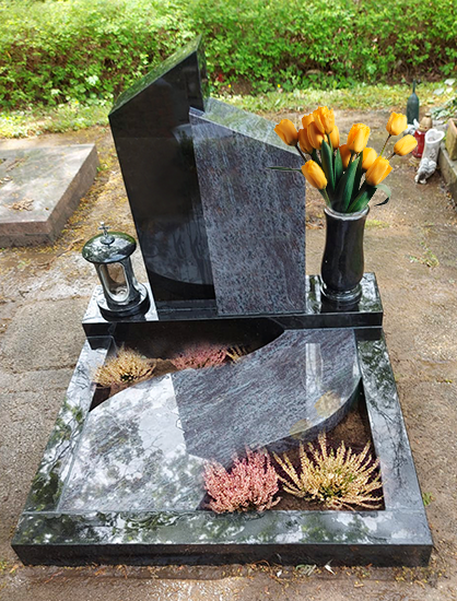 Gedenkgrab aus schwarzem Granit mit Blumen und kleinen Kerzenlaternen in einer Gartenanlage