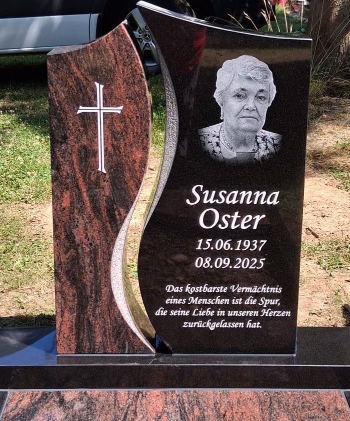 Schwarzer Granitgrabstein mit weißem Kreuz, Porträt und dem Namen Susanna Oster sowie den Lebensdaten.