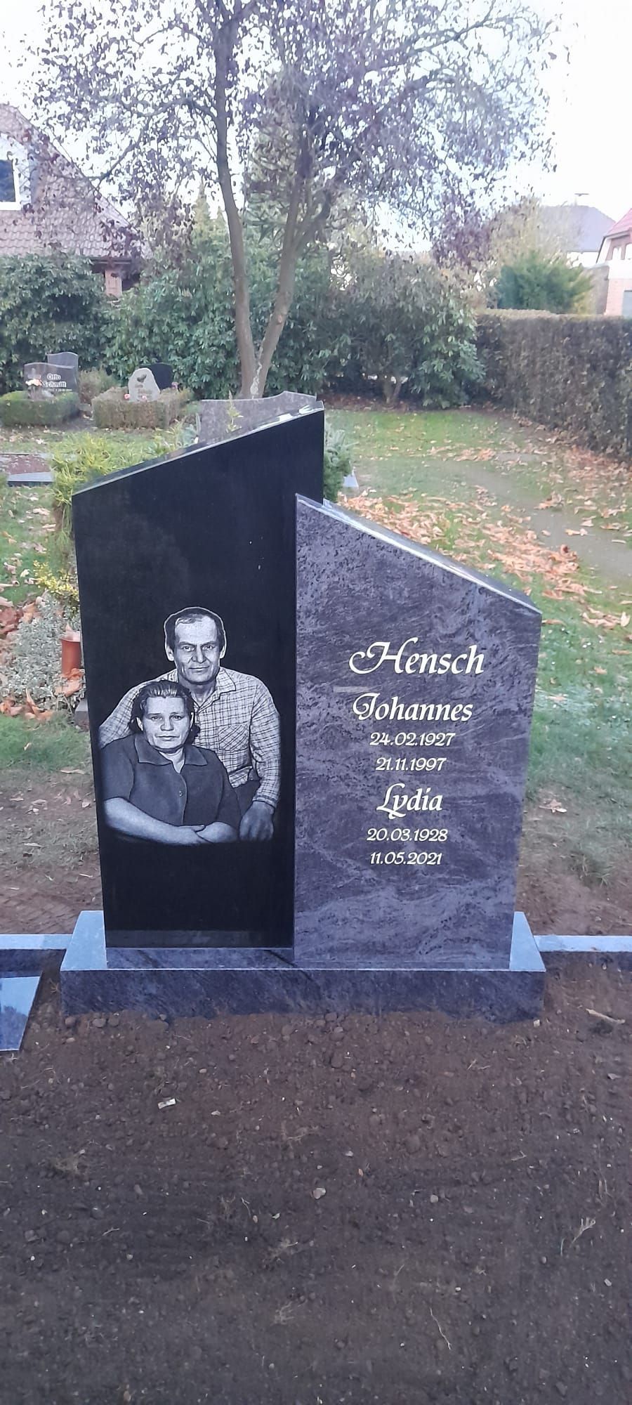 Schwarzer Granitgrabstein mit eingraviertem Porträt in einer Gartenfriedhofsanlage