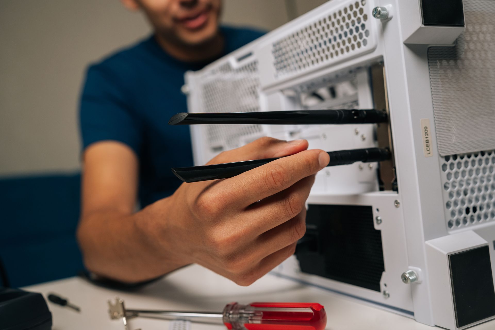 Mann baut einen Computer zusammen, hält Antennen und arbeitet in einem weißen PC-Gehäuse.