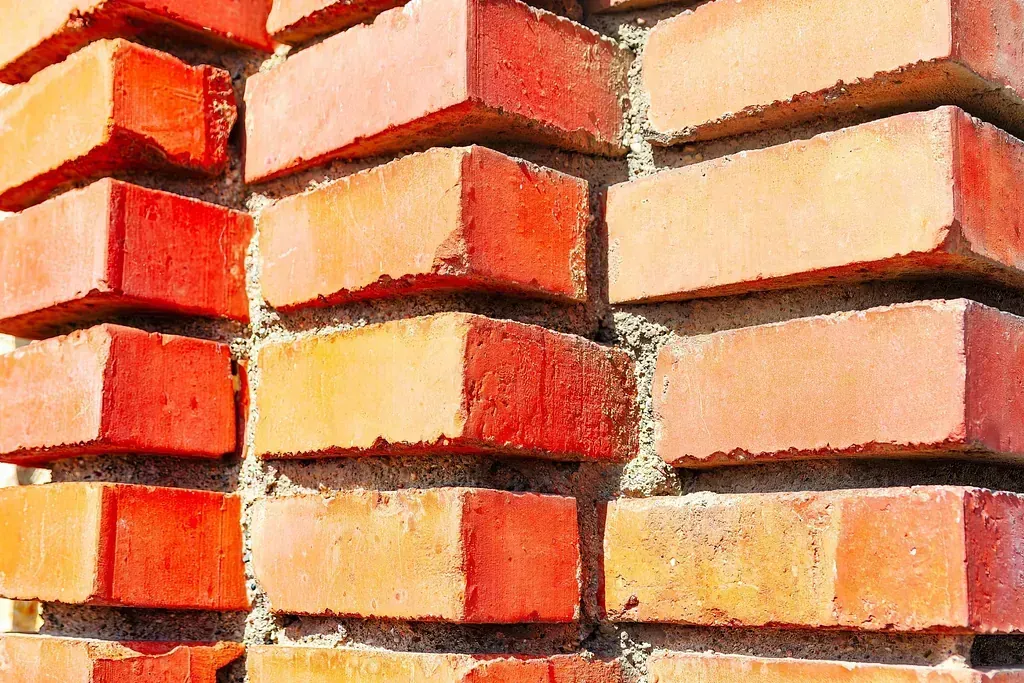 Un primer plano de una pared de ladrillos con ladrillos apilados uno encima del otro.