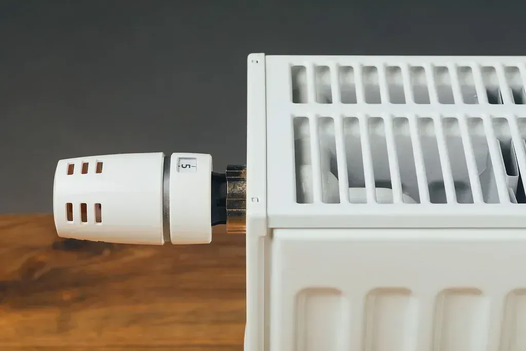 Un primer plano de un termostato en un radiador sobre una mesa de madera.