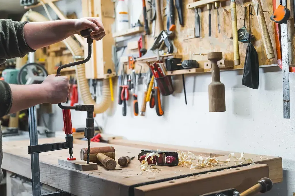 Un hombre está trabajando en un trozo de madera en un taller.