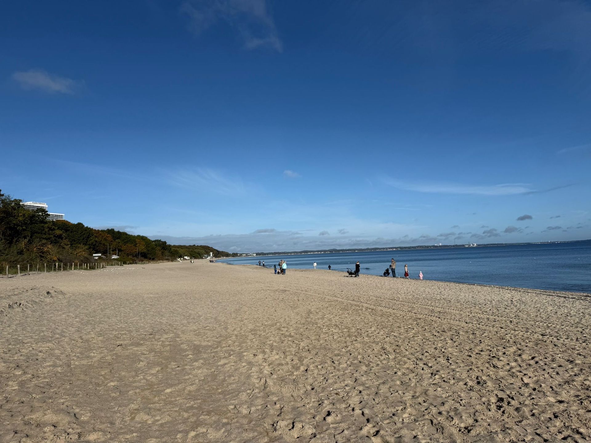 Sandstrand mit Menschen, Meer und blauem Himmel.