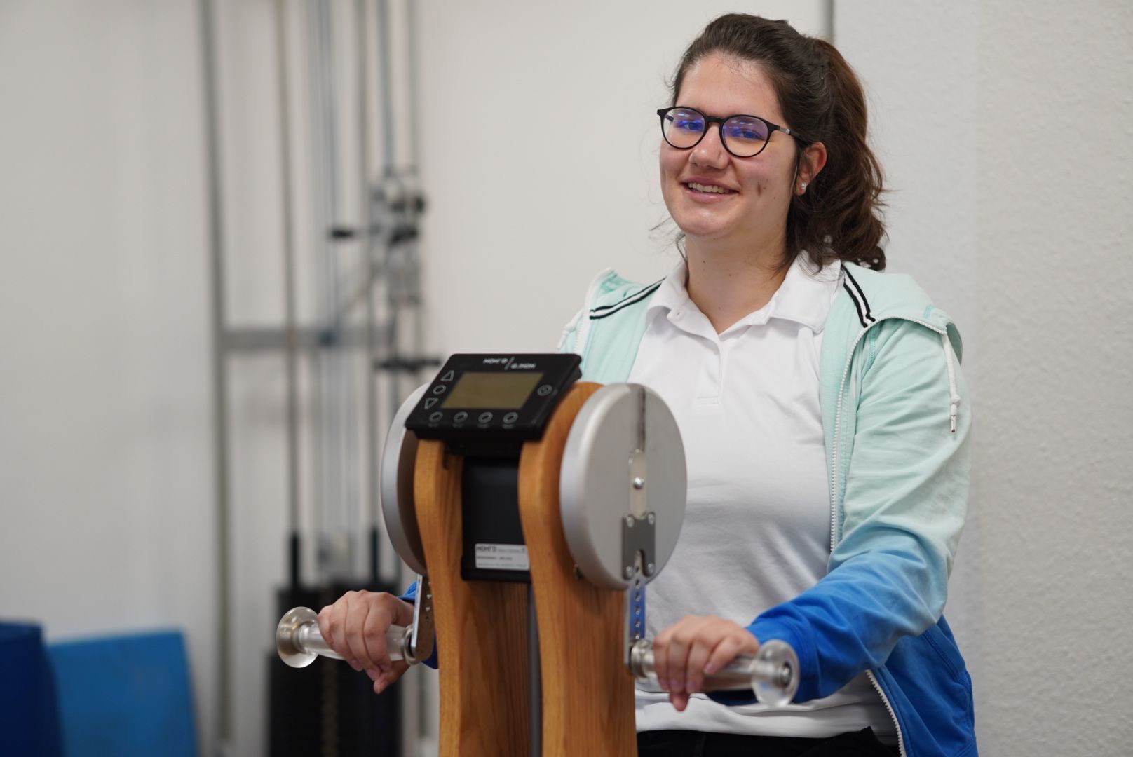 Eine Frau steht vor einer Maschine und hält ein Paar Hanteln.