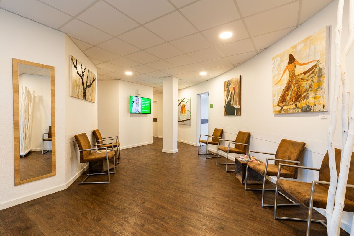 Ein Wartezimmer mit vielen Stühlen und einem Spiegel.