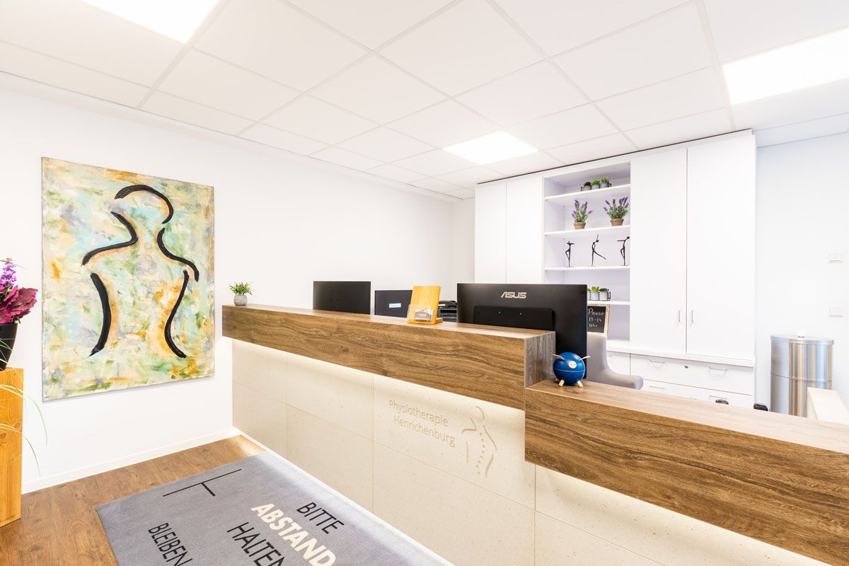 Ein Rezeptionsbereich mit einem Holztresen und einem Gemälde an der Wand.