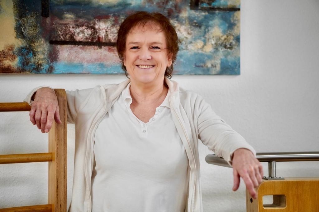 Eine Frau lehnt an einem Holzgeländer und lächelt.