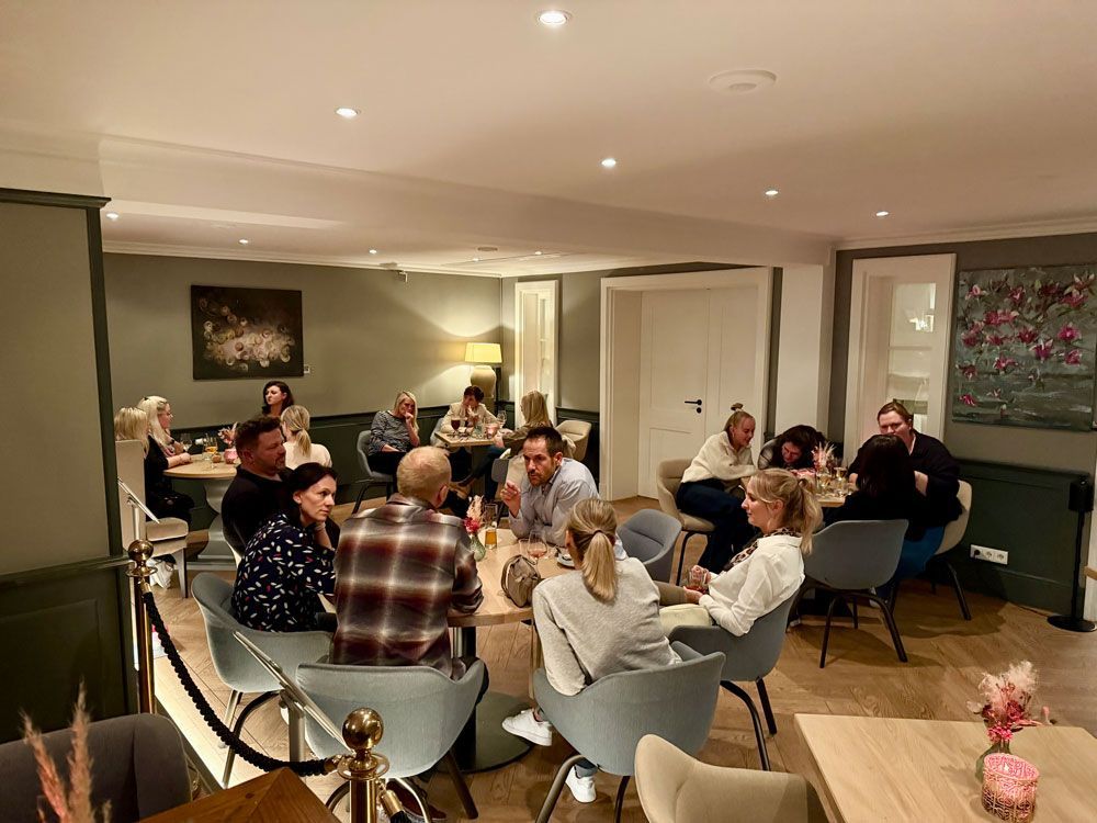 In einem schwach beleuchteten Restaurant versammelten sich Menschen um Tische, unterhielten sich und sprachen miteinander.