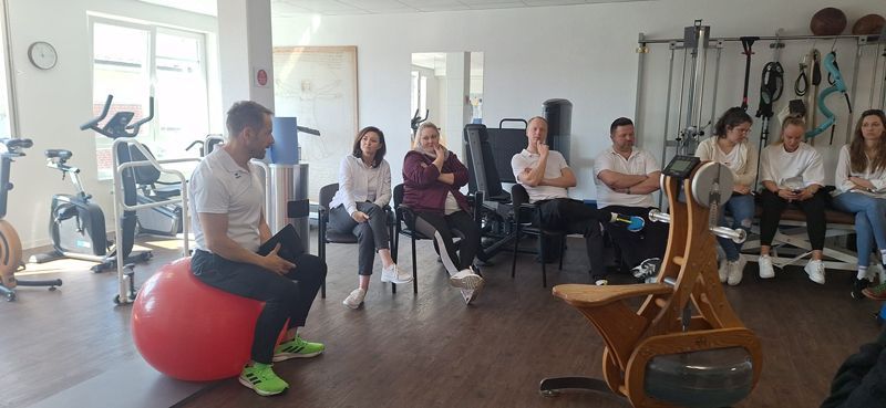 Eine Gruppe von Menschen sitzt in einer Turnhalle im Kreis.