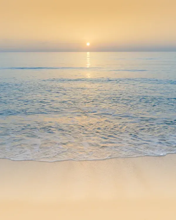 Auringonnousu tyynen meren yllä lempeillä aalloilla ja hiekkarannalla