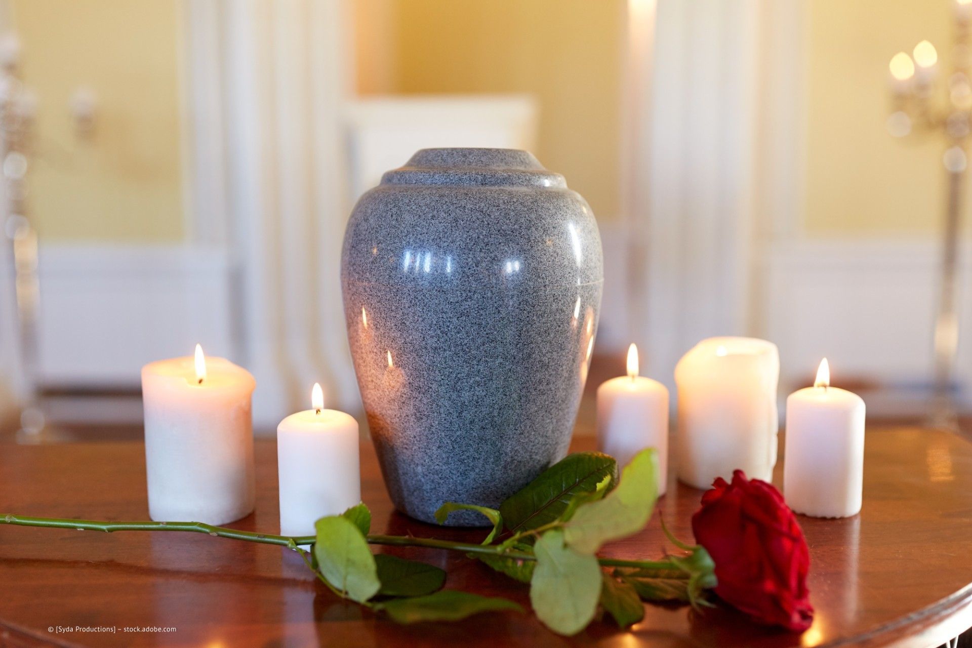 Urne umgeben von Kerzen und Blumen
