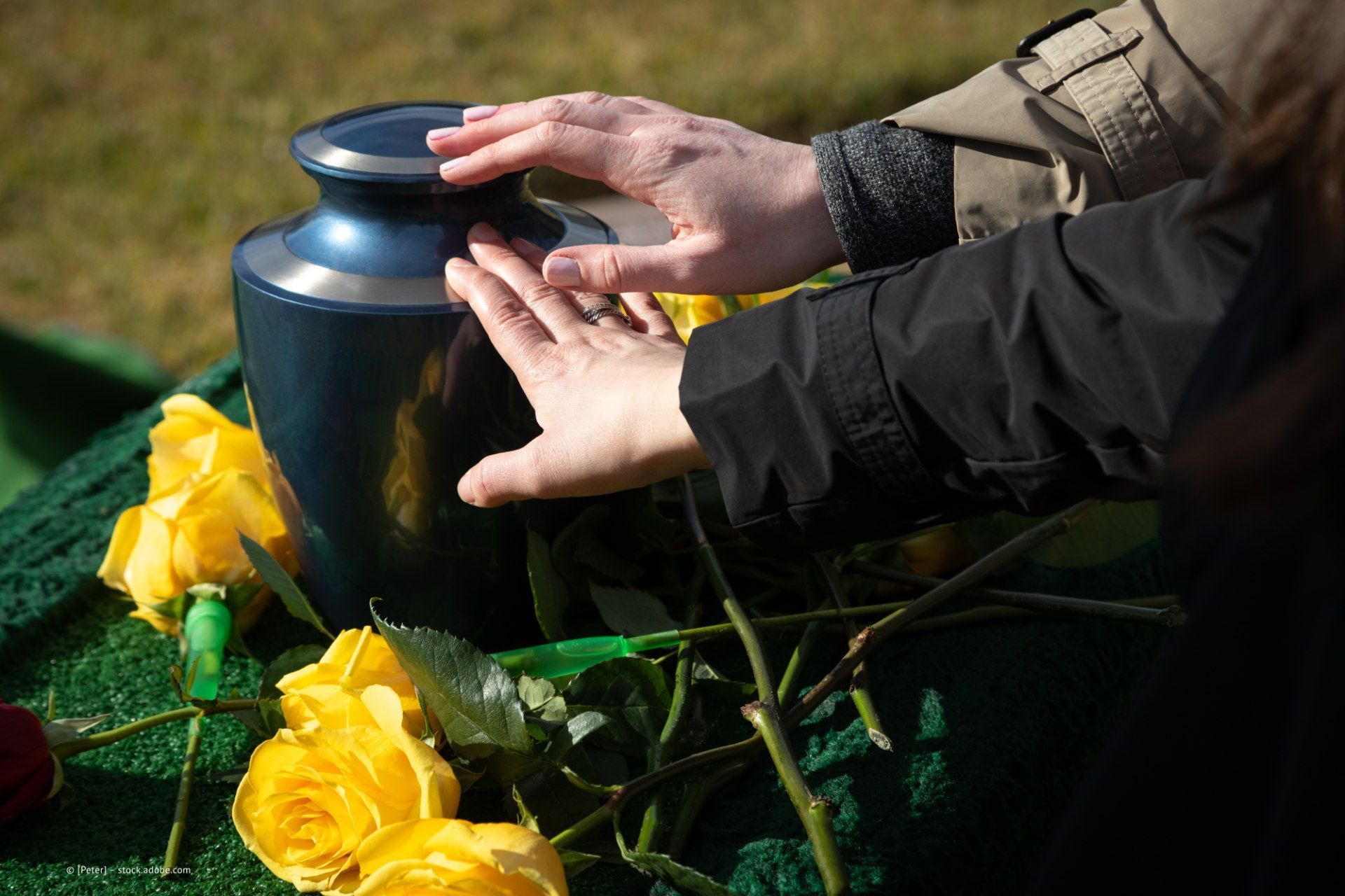 Personen berühren eine Urne