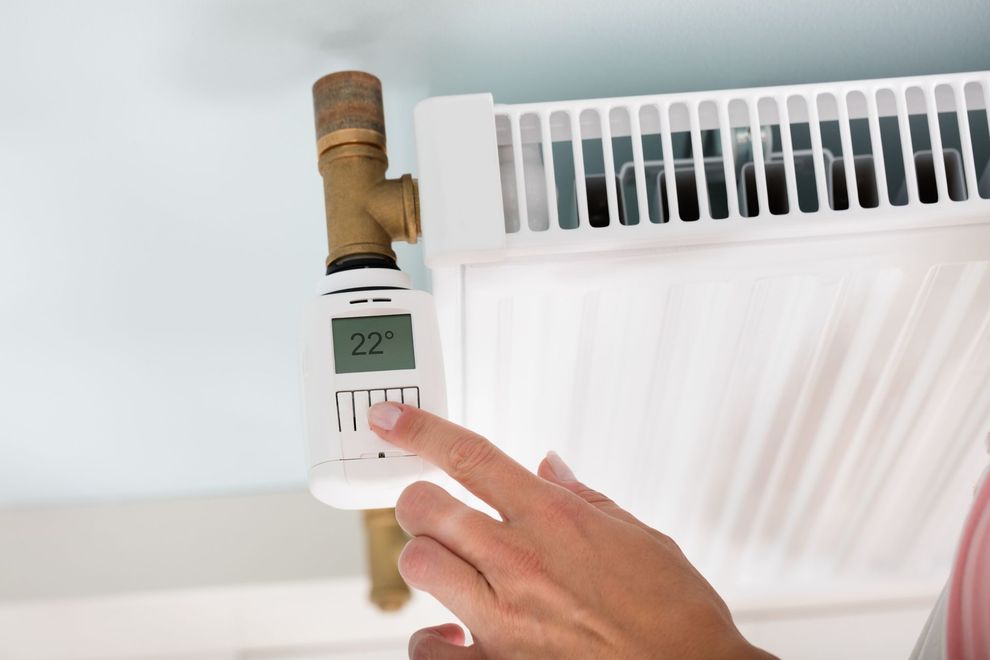 Una persona está ajustando un termostato en un radiador.