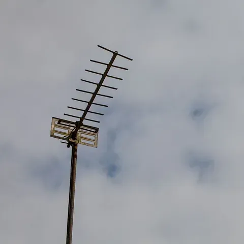 Antena de televisión en un poste de madera contra un cielo nublado.
