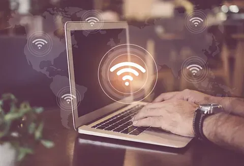 Persona escribiendo en una computadora portátil con superposición de símbolo wifi.