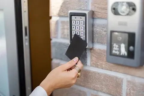 La persona pasa una tarjeta de acceso negra por el teclado para ingresar a un edificio.