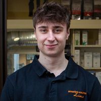 Ein Mann in schwarzem Poloshirt steht in einem Türrahmen und schaut den Betrachter an.