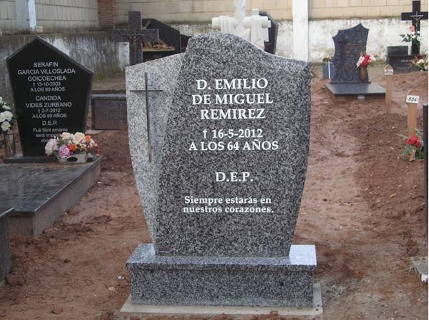 Lápida de D. Emilio de Miguel Ramírez con inscripción, cruz y flores en un cementerio.