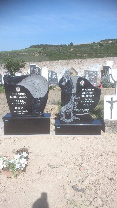Dos lápidas de granito negro en un cementerio, cada una con imágenes e inscripciones grabadas.