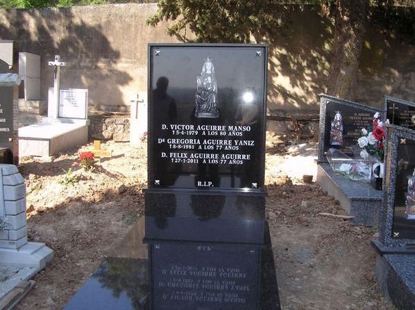 Lápida de granito negro en un cementerio; nombres y fechas están grabados.