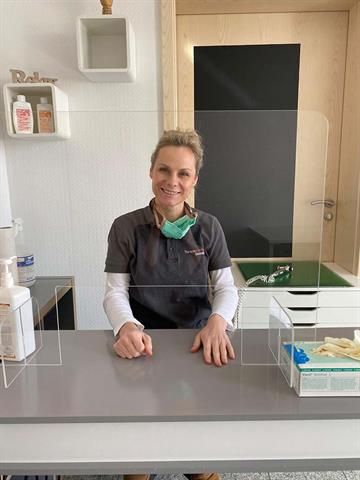 Eine Frau sitzt an einem Tresen in einer Zahnarztpraxis.