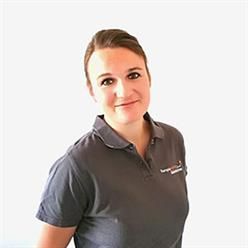 Eine Frau trägt ein graues Poloshirt und lächelt in die Kamera.
