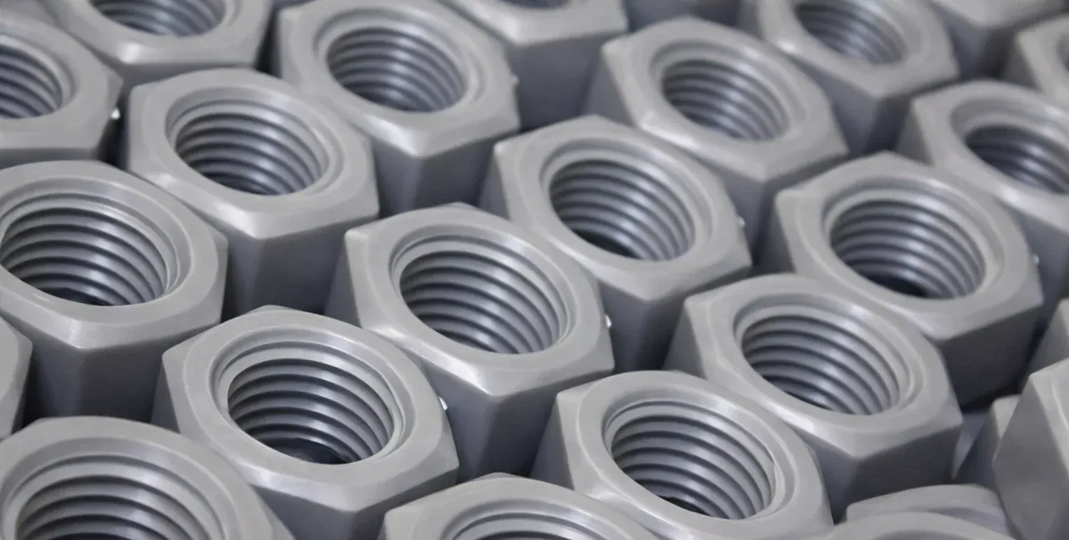 Un trabajador de una fábrica sostiene un cubo de plástico azul, con pilas de cubos idénticos cerca, sobre una mesa.