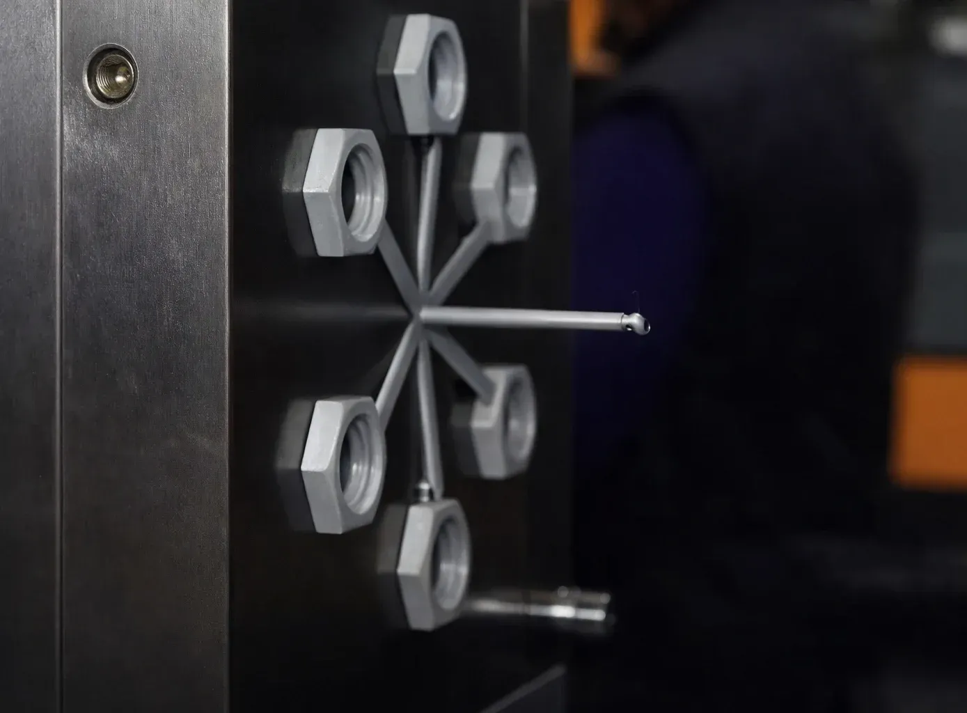 Una pieza mecánica que presenta un patrón en forma de estrella de seis tuercas grises conectadas