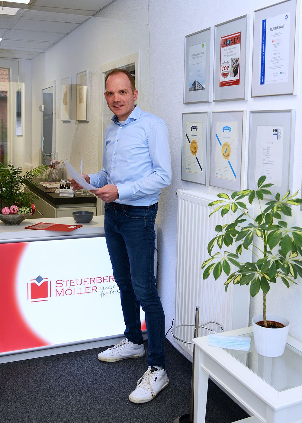 Ein Mann steht in einem Raum vor einem Tresen und hält ein Stück Papier in der Hand.