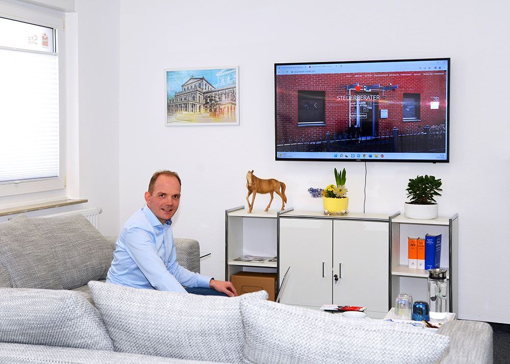 Ein Mann sitzt auf einer Couch vor einem Fernseher.