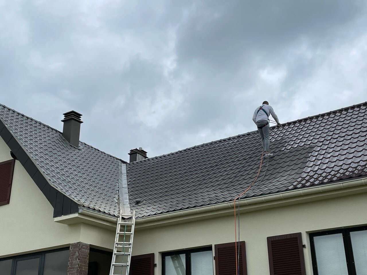 Couvreur sur la toiture en train de peindre par projection