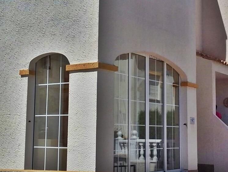 Un edificio blanco con una puerta corrediza de vidrio y ventanas arqueadas.